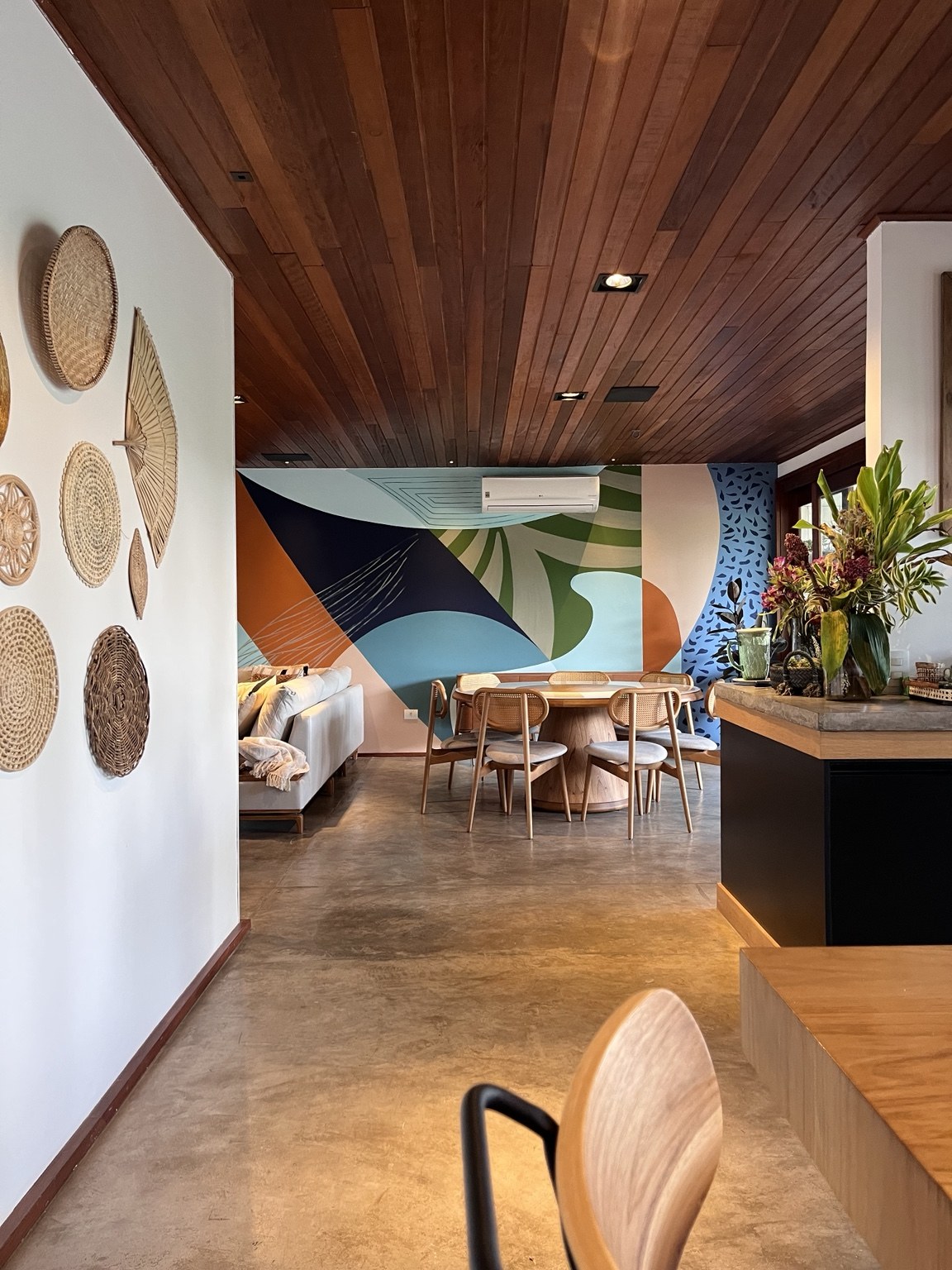 Intervenção artística em espaço de convivência com mural geométrico e mobiliário